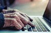 Old man's hands typing on laptop