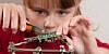 A child cuts excess wire from electronic components soldered to an upside down printed circuit board