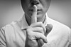 man with finger pressed to lips