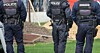 Police officers in bodu armour mill around in field