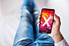 Someone holding an Apple iPhone with an X displayed on it
