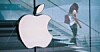Someone walking down some steps away from the Apple logo large on the side of a building