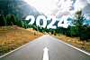 A road leading ahead with 2024 written over a forest landscape