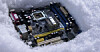 A PC motherboard sitting in snow