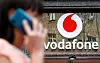 Someone walking by a Vodafone shop while using a cellphone