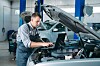 A mechanic tuning a car engine using a laptop