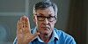 Sixty-something man raises palm as if telling the viewer to stop