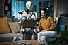 A friendly robot working with someone on a laptop at home