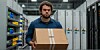 tech worker standing in a datacenter carrying a cardboard box and looking angry and calculating