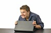 Man with guilty grin carefully closes laptop