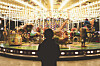 A kid standing in front of a merry-go-round