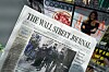 Someone holding up a copy of the Wall Street Journal newspaper at a newsstand