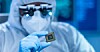 Someone inspecting a chip in a semiconductor factory clean room