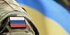 Flag of Russia on military uniform and flag of the Ukraine at background.