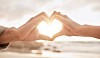 Two people holding hands in a way that looks like a heart