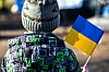 A kid in warm clothes holds a flag of Ukraine
