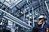 Man talks on ohone next to outdoor pipeline, Photo by Shutterstock