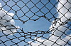 hole_in_fence_sky_clouds