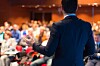 man gives lecture faces crowd