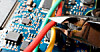 Wire cutters cutting a red wire over a circuit board