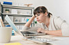 Tired disappointed woman working at office desk with a laptop