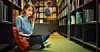 Someone sitting in a library with a generic laptop