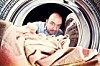 Man loads in blanket into the washing machine. Photo by Shutterstock