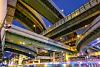 Intersecting above-ground highways (skyways) constructed in intricate pattern, shot from below at night. Photo by Shutterstock