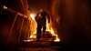 A firefighter runs up some stairs that are ablaze