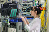 An engineer works on a laptop surrounded by a tangle of cables in a datacenter