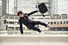 Business man with suitcase jumping over urban obstacles