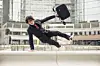 Business man with suitcase jumping over urban obstacles