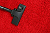 A vacuum cleaner going over red carpet