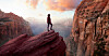 Someone standing on the edge of a rock against some clouds