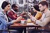 Young people stare vacantly at their mobile phones/ cellphones