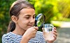 Girl looking at a glass of water through a magnifying glass