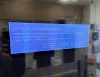 A blue Windows update screen displayed on a monitor inside a post office.