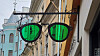Oversized green sunglasses sign mounted on a building wall along a street.