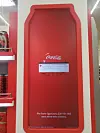 Red Coca-Cola display panel with a warning message about low storage space, shown inside a store.