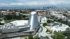 California Science Center in Los Angeles, a silver futuristic building beside low-rise buildings with a city skyline in the distance.