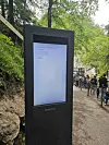 A tall digital sign on a path outdoors shows a network error near a queue of visitors.