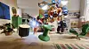 Colorful room with sculptural figures, green chairs and a central green stool.