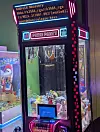 Arcade claw machine with plush toys and an Android recovery screen glowing above the prize compartment.