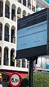 Digital sign in Lloret de Mar displays Ubuntu update and Firefox welcome messages beside a resort building.