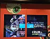 Red-framed storefront screens show a festive character and an ad for Colin the Caterpillar chocolate treats.